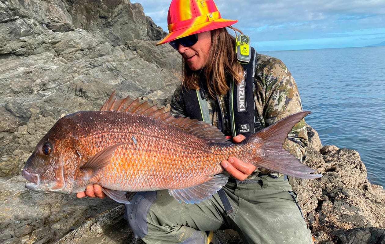 Man wearing a PLB holding a large snapper