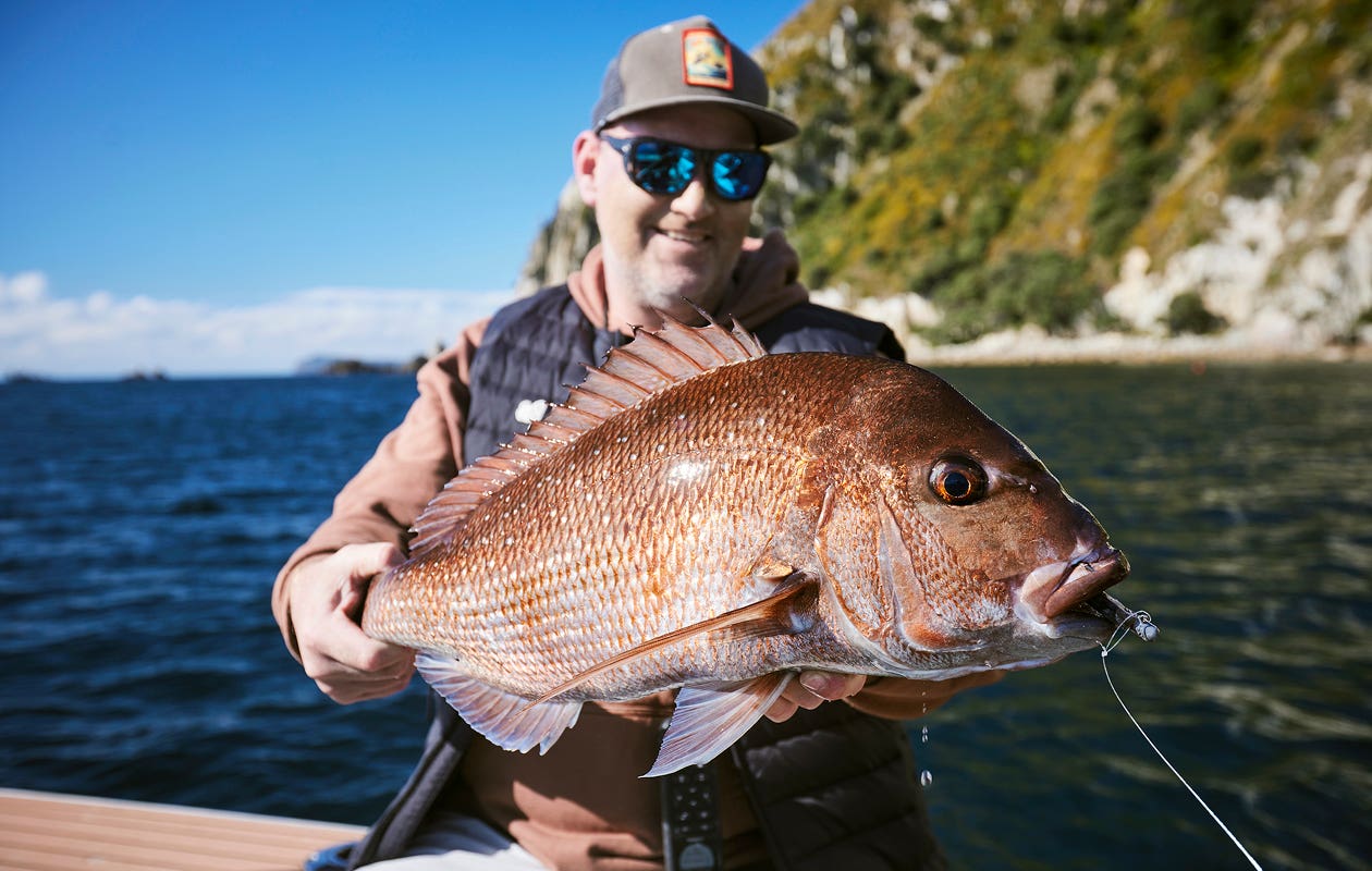 Man wearng a hat and sunglasses holding a large snapper