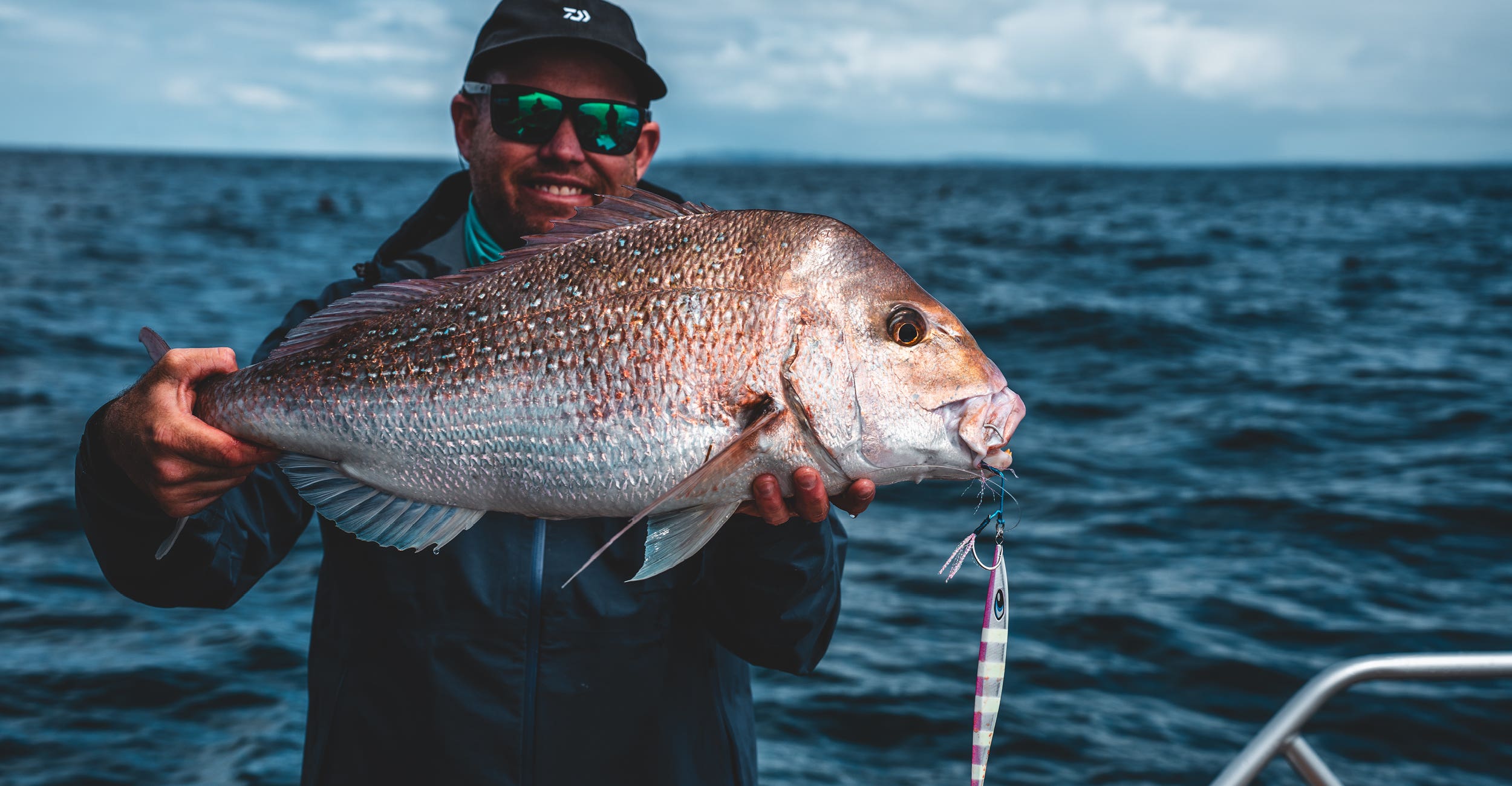 Man in a blue jacket holding a large snapper