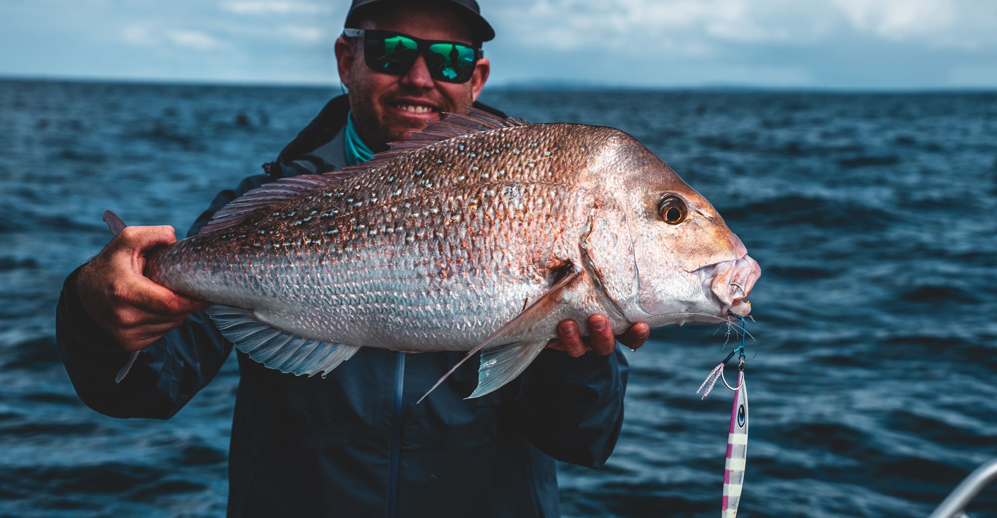 Man in a blue jacket holding a large snapper