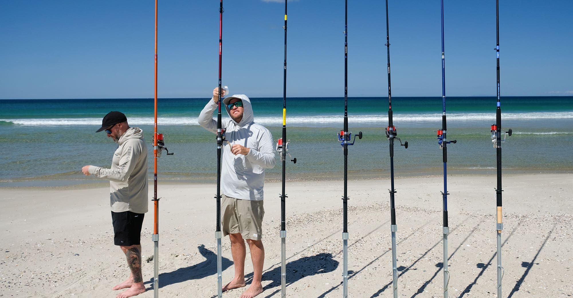 People rigging surfacting rods at the beach